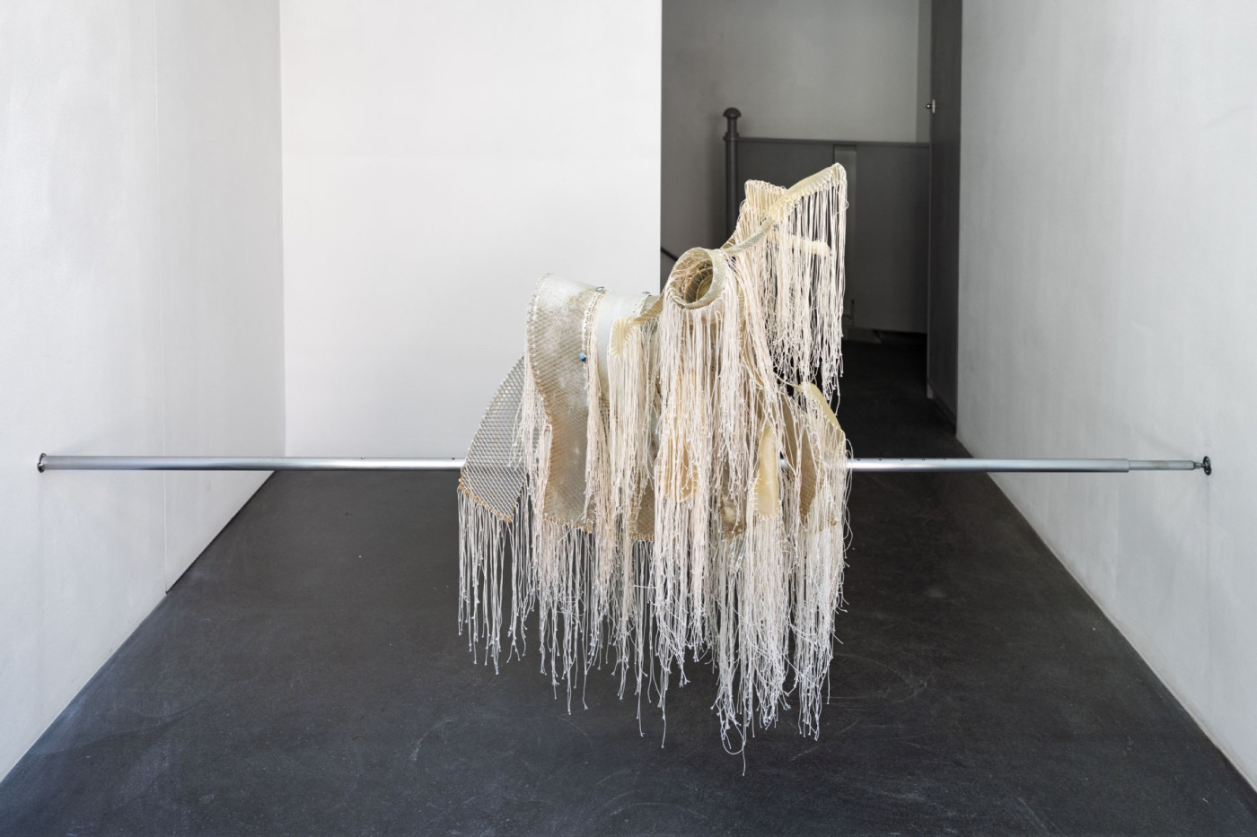 Fringed sculpture hanging from a steel rod
